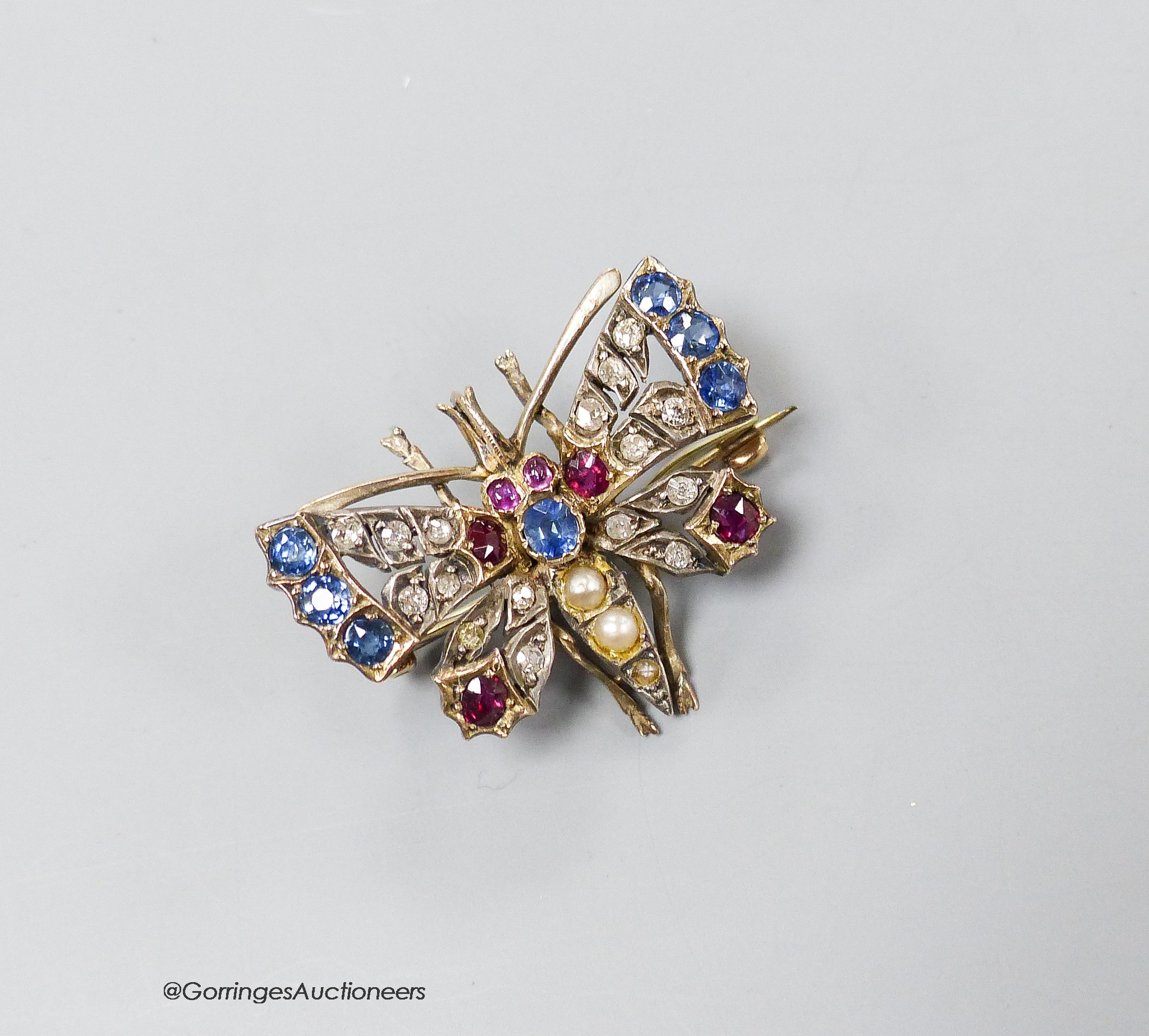 An Edwardian yellow and white metal, ruby, sapphire, diamond and split pearl set butterfly pendant brooch, 32mm, gross 7.9 grams.